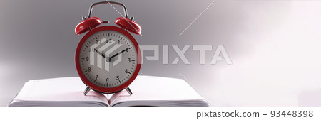 Red retro clock stand on top of open notebook or book Red retro clock stand on top of open notebook or book 93448398