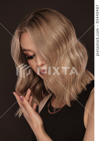 Beautiful blond girl with a perfectly curls hair, and classic make-up. Beauty face and hair. 93449487