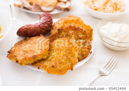 Potato pancakes with fried sausage on white plate 93452484