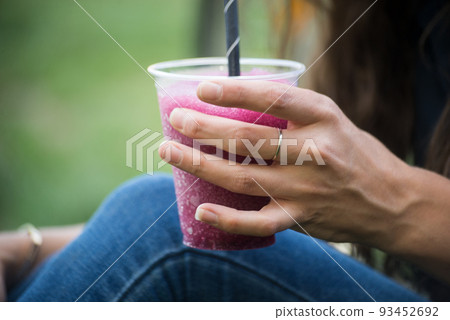 Closeup of pilled ice in hand on young woman in a public garden 93452692