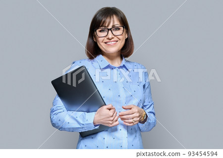 Smiling business woman with laptop on gray background Smiling business woman with laptop on gray background 93454594