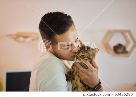 Young man in t shirt holding a cat. 93456290