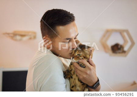 Young man in t shirt holding a cat. 93456291