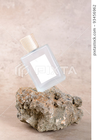 Transparent bottle of perfume with white labels on stone podium on beige terracotta background with dry flower. Transparent bottle of perfume with white labels on stone podium on beige terracotta background with dry flower. 93456962