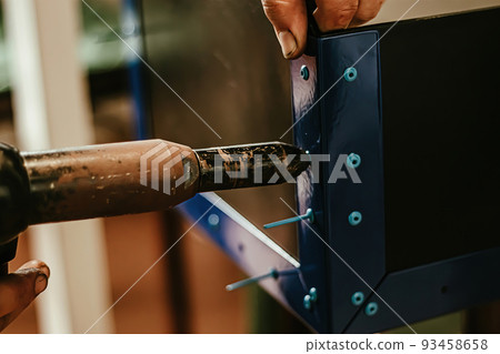 Male worker uses electric riveting gun. Hand holding  riveting m 93458658