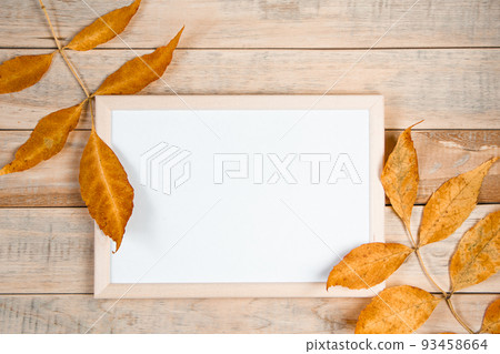 Hello autumn concept. Empty frame mock up on wooden background and yellow fallen leaves. Hello autumn concept. Empty frame mock up on wooden background and yellow fallen leaves. 93458664
