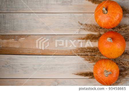 Autumn minimalistic background. Ripe pumpkins and ears of wheat on wooden boards. Harvest and Thanksgiving concept. Autumn minimalistic background. Ripe pumpkins and ears of wheat on wooden boards. Harvest and Thanksgiving concept. 93458665