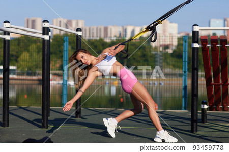 Sports woman with short hair doing crossfit push ups with fitness straps outside. Sports woman with short hair doing crossfit push ups with fitness straps outside. 93459778