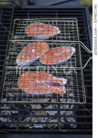 salmon steaks on grill are coking on the firewood in the backyard. salmon steaks on grill are coking on the firewood in the backyard. 93465140