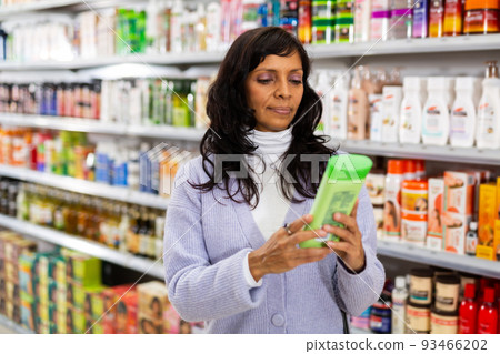 Hispanic woman choosing hair care treatments in cosmetics store Hispanic woman choosing hair care treatments in cosmetics store 93466202