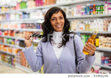 Adult Latina choosing haircare cosmetics in specialized boutique 93466206