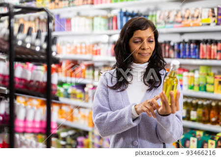 Woman buying new oil in hair care store Woman buying new oil in hair care store 93466216