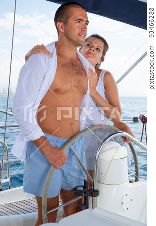 Woman and man steering yacht along shoreline of Spain 93466288