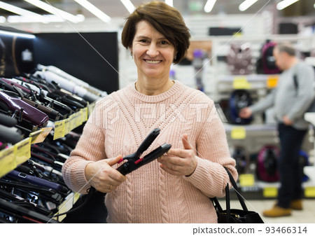 Portrait of a European woman choosing an electric styler Portrait of a European woman choosing an electric styler 93466314