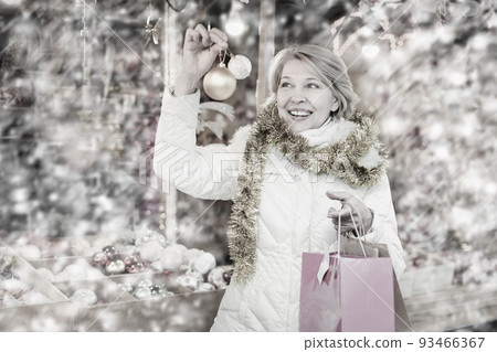 Smiling woman choosing Christmas toys at Christmas market 93466367