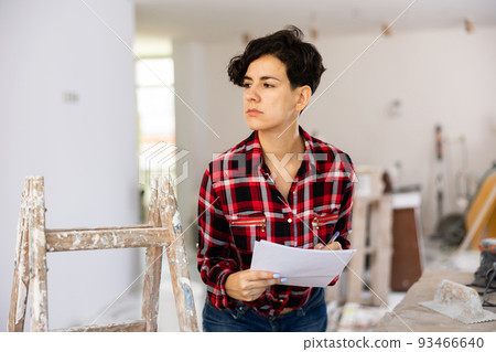 Woman designer checking documents during repair works Woman designer checking documents during repair works 93466640