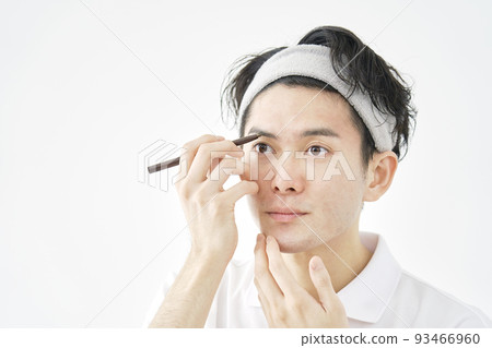 A man drawing eyebrows with an eyebrow pencil on a white background A man drawing eyebrows with an eyebrow pencil on a white background 93466960