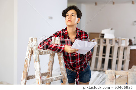 Woman designer checking documents during repair works 93466985