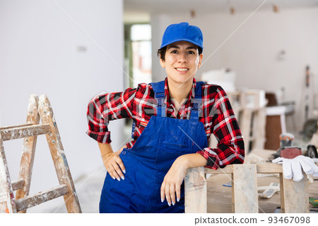 Young woman builder in work clothes posing in apartment during repair works 93467098