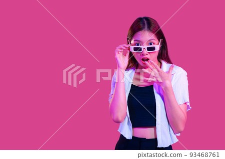 Young asian woman in black tank top and white shirt wearing sunglasses posing wow and surprised isolated pink color background with copy space 93468761