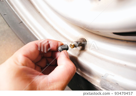 The car driver manually remove the tire valve cap 93470457