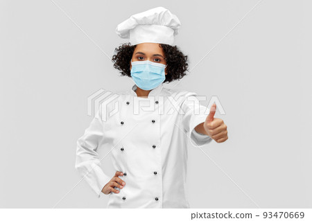 female chef in medical mask showing thumbs up 93470669