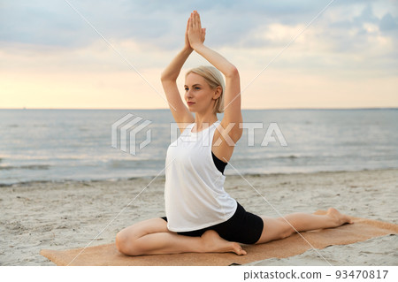 woman doing yoga pigeon pose on beach woman doing yoga pigeon pose on beach 93470817