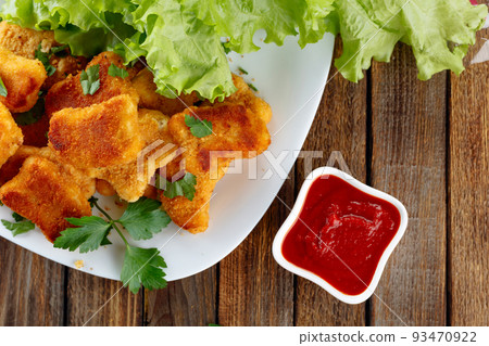 Fried chicken nuggets with ketchup sprinkled with chopped parsley. 93470922