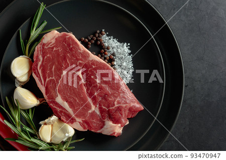 Raw beef meat steak with rosemary, garlic, salt, and pepper. 93470947