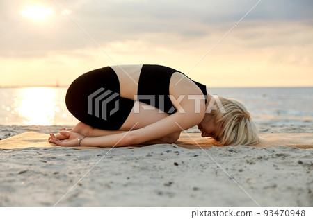 woman doing yoga child pose on beach 93470948