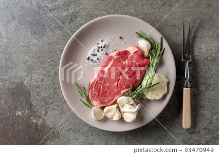Raw beef steak with rosemary, garlic, salt, and pepper. 93470949