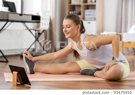 teenage girl with tablet pc exercising at home 93470950