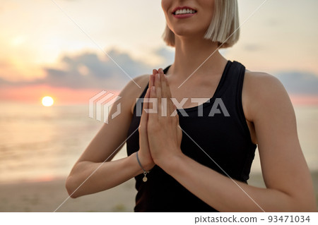 close up of woman meditating on beach over sunset 93471034