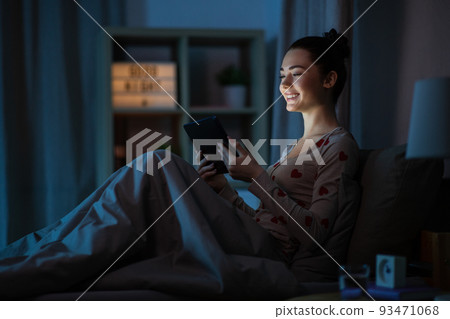 teenage girl with tablet pc in bed at night teenage girl with tablet pc in bed at night 93471068