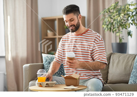 smiling man with takeaway food and drinks at home smiling man with takeaway food and drinks at home 93471129