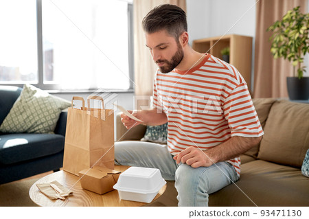 man with bill checking takeaway food order at home 93471130