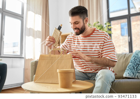 smiling man unpacking takeaway food at home 93471133