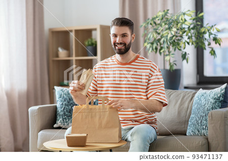 smiling man unpacking takeaway food at home 93471137