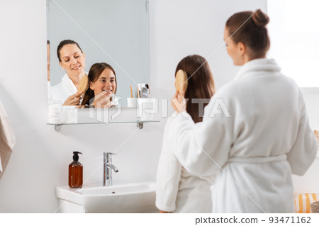 mother and daughter brushing hair at bathroom mother and daughter brushing hair at bathroom 93471162