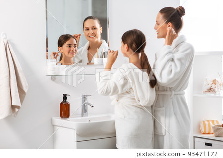 mother and daughter cleaning ears with cotton swab mother and daughter cleaning ears with cotton swab 93471172
