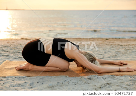 woman doing yoga child pose on beach 93471727