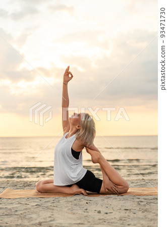 woman doing yoga mermaid pose on beach woman doing yoga mermaid pose on beach 93471730