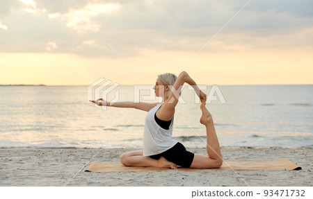 woman doing yoga pigeon pose on beach woman doing yoga pigeon pose on beach 93471732