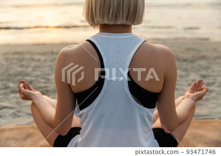 woman meditating in lotus pose on beach woman meditating in lotus pose on beach 93471746