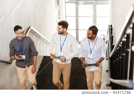 men with conference badges walking upstairs 93471786