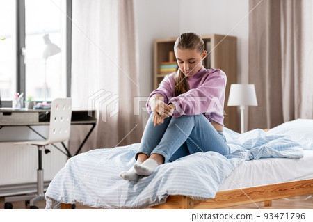 sad girl sitting on bed at home 93471796