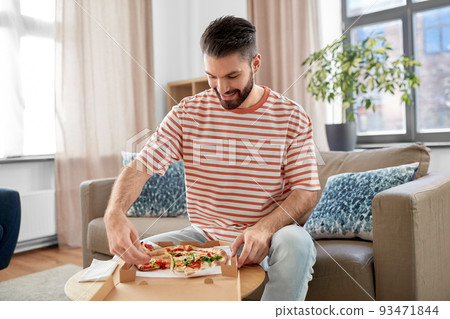 man opening box and eating takeaway pizza 93471844