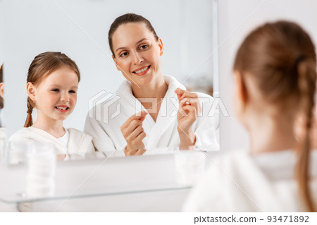 mother and daughter with floss cleaning teeth 93471892