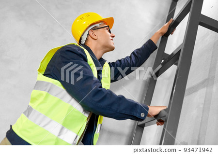 builder or worker in helmet climbing ladder 93471942