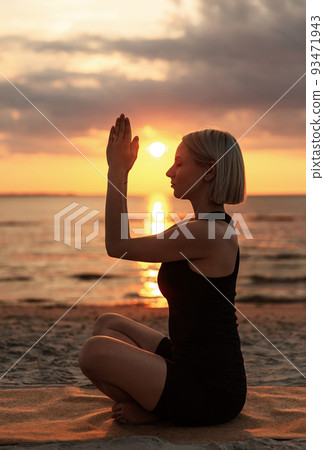 woman meditating in easy pose on beach woman meditating in easy pose on beach 93471943